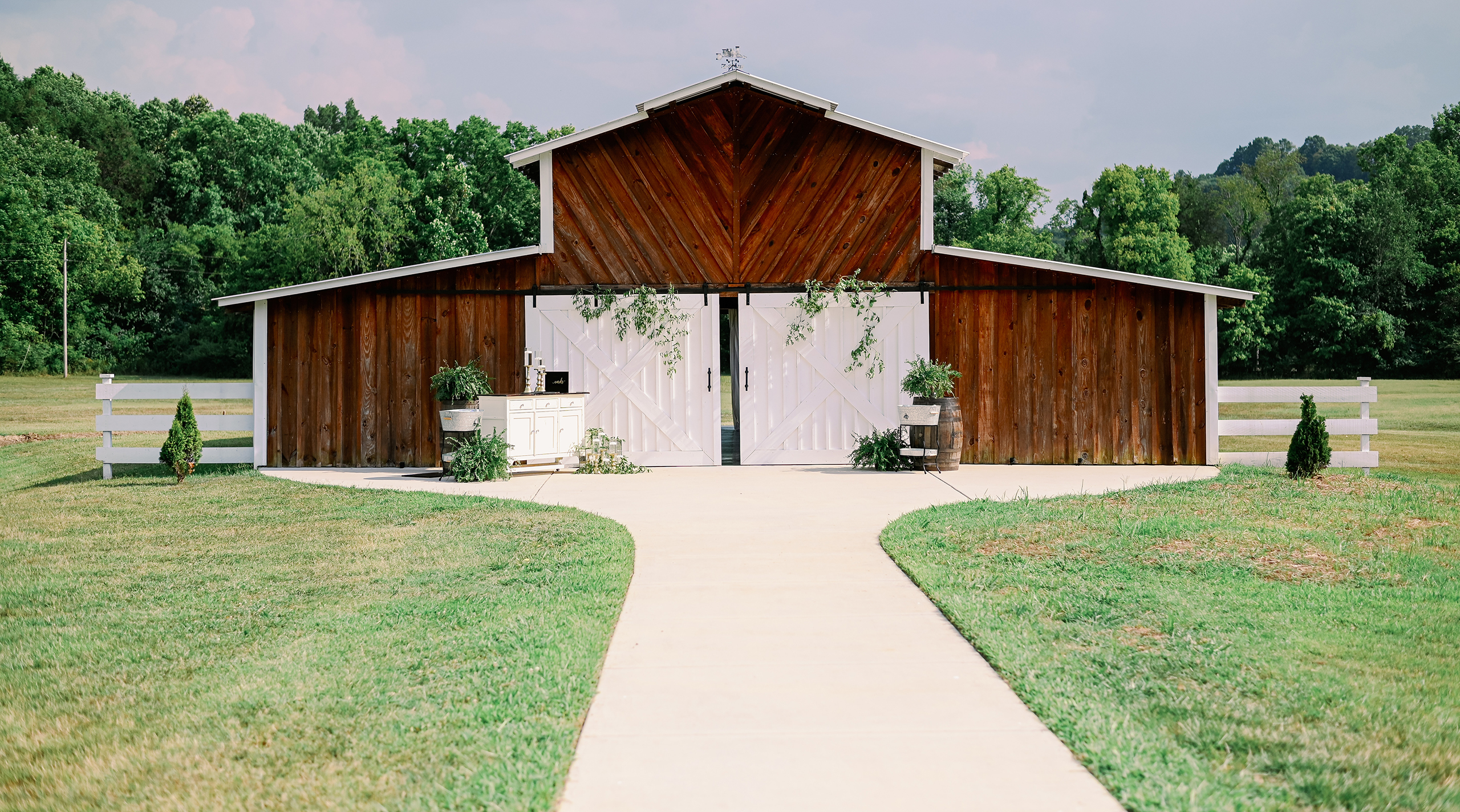 Rustic wooden barn wedding venue with white doors and greenery accents in Huntsville, Alabama.